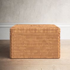 a brown wicker box sitting on top of a wooden floor next to a white wall