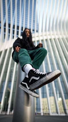 a person sitting on top of a pole with their feet in the air and wearing sneakers