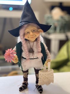 a small figurine wearing a hat and holding a flower in it's hand