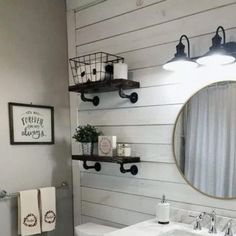 a bathroom with white walls and wood flooring is decorated in black and white, while a round mirror hangs above the sink