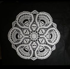 a white doily sitting on top of a black cloth covered in crochet