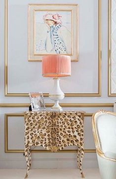 a leopard print table with a pink lamp and painting on the wall in front of it