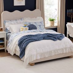 a bedroom with blue walls and white bedding