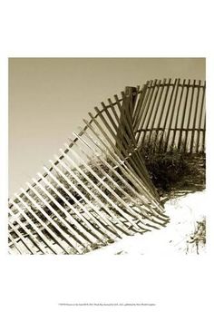 a wooden fence sitting on top of a sandy beach next to the ocean with grass growing out of it