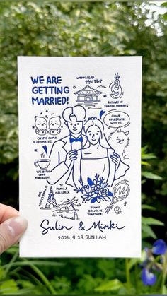 a hand holding up a card with the words we are getting married in blue ink