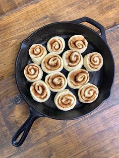 cinnamon buns in a cast iron skillet on a wooden table, ready to be cooked