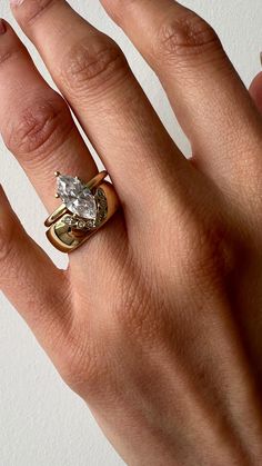 a woman's hand wearing a gold ring with a pear shaped diamond on it