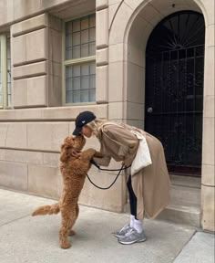 a person is petting a dog on the side walk near a building with an arched doorway