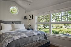 a bedroom with a large bed and two windows in the wall next to each other