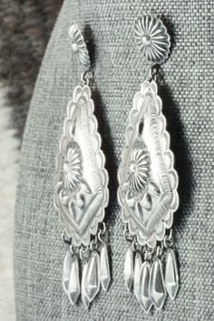 These sterling silver earrings were made by Navajo silversmith Terry Charlie. The back of the earrings are signed T. Charlie and stamped sterling.Length: 2 7/8"Width: 1 3/8"Free shipping on all orders! We ship with USPS and always include tracking. All orders ship within a day of payment.Returns are accepted up to 30 days after you receive your order. Just send us a message. Our shop offers cash back or store credit. The item must be returned in new condition. Western Style Teardrop Silver Jewelry, Western Style Silver Teardrop Jewelry, Western Style Concho Dangle Jewelry, Southwestern Silver Teardrop Earrings, Southwestern Silver Drop Earrings, Silver Southwestern Drop Earrings, Vintage Sterling Silver Etched Earrings, Southwestern Style Silver Drop Earrings, Vintage Etched Sterling Silver Earrings