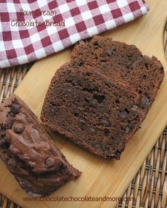 two pieces of chocolate bread on a cutting board with a red and white checkered towel