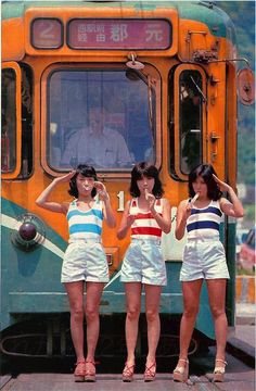 three girls standing in front of a train