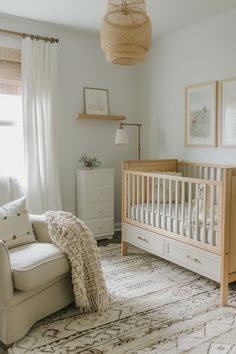 a baby's room with a crib, chair and rug on the floor