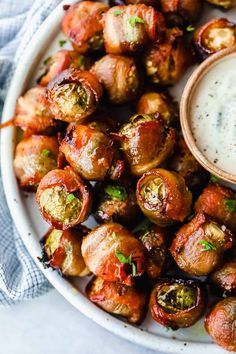 a white plate topped with brussel sprouts next to a small bowl of ranch dressing