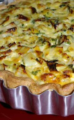 a pie with cheese and other toppings in a metal pan on a red table