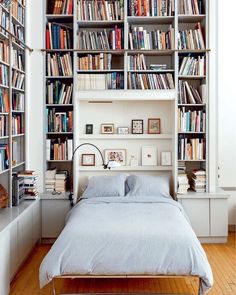 a bed sitting under a book shelf filled with books