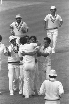 a group of men standing around each other on top of a field