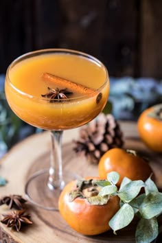 two glasses filled with orange juice sitting on top of a wooden table next to pumpkins