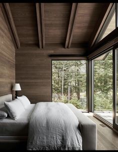 a large bed sitting in a bedroom next to a tall wooden wall with windows on each side