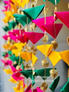 colorful paper decorations hanging from strings on the side of a building with gold and green accents