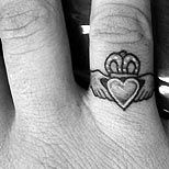 a person's hand with a crown and heart tattoo on the middle finger,