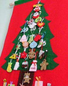 a christmas tree made out of felt on a red background with other items hanging from it