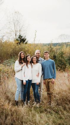 a family poses for a photo in the tall grass at their fall family portrait session