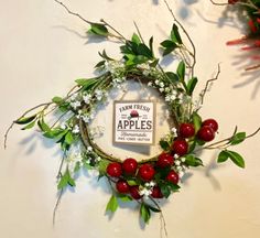 a wreath with berries and greenery hanging on the wall next to a sign that says apple trees