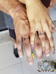 two people with their hands on each other's fingers and one has a heartbeat tattoo