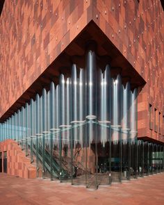 a large building with metal pipes in front of it's entrance and stairs leading up to the second floor