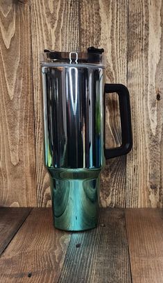 a green and black blender sitting on top of a wooden table next to a wall