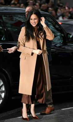 a woman in a tan coat and brown dress