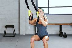 a woman is doing squats with straps on her back and holding the handles up in front of her face