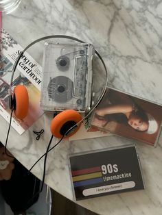 two orange headphones sitting on top of a table next to an mp3 player and magazine