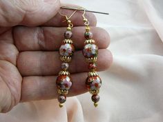 (Internal #EE600-485)  You are bidding on this pair of five bead, 6 and 12mm RED with pink and white flower CLOISONNÉ bead DANGLE EARRINGS with gold tone brass bead and filigree cap accents, on gold tone french wire earrings, 3-1/8" long.This is exactly the pair of earrings you will get.   CLOISONNÉ EARRINGS, CHINA:  Here's how a cloisonné bead is made: A copper body is hammered and welded.  Then wire "cells" (where the word "cloisonné" came from) are formed and soldered on the copper body.  Pre Elegant Multicolor Round Beads Flower Earrings, Elegant Pink Flower Earrings With Dangling Beads, Gold Flower-shaped Earrings With Dangling Beads, Gold Flower-shaped Jewelry With Dangling Beads, Gold Dangle Beaded Earrings With Bead Caps, Bohemian Gold Earrings With Bead Caps, Bohemian Gold Flower Bead Earrings, Bohemian Gold Flower Earrings With Round Beads, Pink Earrings With Gold Beads