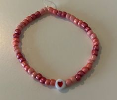 Pink beads with heart bead. Made with stretchy string. Heart-shaped Beaded Stretch Bracelet For Friendship, Casual Handmade Heart Bracelet With Round Beads, Heart-shaped Letter Beads For Gifts, Casual Adjustable Stretch Bracelet With Heart Beads, Casual Beaded Bracelets With Heart Charm, Heart-shaped Beaded Stretch Bracelet Gift, Heart-shaped Beaded Stretch Bracelet For Gift, Casual Beaded Bracelets With Heart Charm For Friendship, Heart-shaped Stretch Bracelet With Heart Beads For Friendship