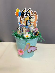 a blue bucket filled with lots of cartoon character cut outs on top of a table