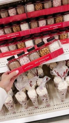 a person is picking up some cupcakes from the shelf in a store with other items