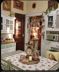 an old fashioned kitchen with white cabinets and green table cloth on the dining room table