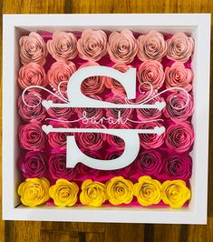 paper flowers are arranged in a box with the letter g on it's side