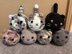 several crocheted cats sitting next to each other in front of a beige wall