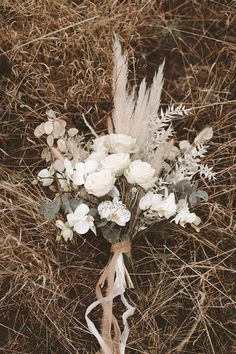 a bouquet of flowers sitting on top of dry grass in the middle of some brush