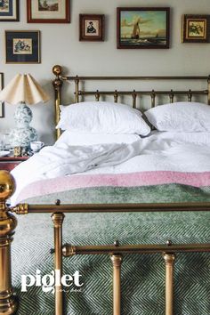 a bed with white sheets and pillows in a bedroom next to pictures on the wall