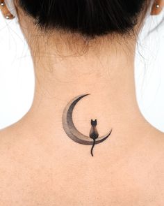 a woman with a cat on her back neck is looking up at the moon tattoo