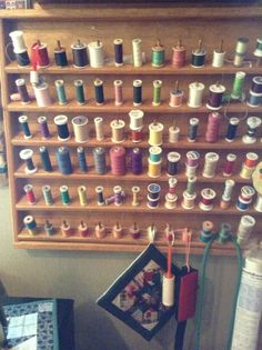 there are many spools of thread hanging on the wall