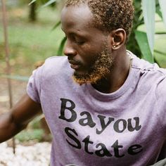 a man holding a frisbee in his right hand and wearing a bayou state t - shirt