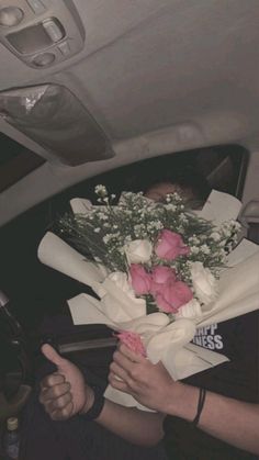 a woman holding flowers in her hand while sitting inside a car