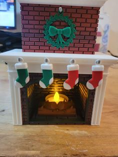 a small fireplace with stockings hanging from it's sides and a christmas wreath on top