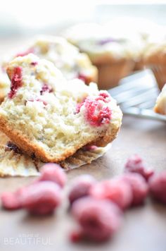 muffins with cranberry filling sitting on a table next to other muffins