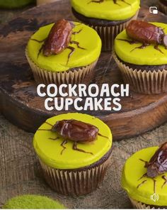 cupcakes with yellow frosting and brown bugs on them, sitting on a wooden tray